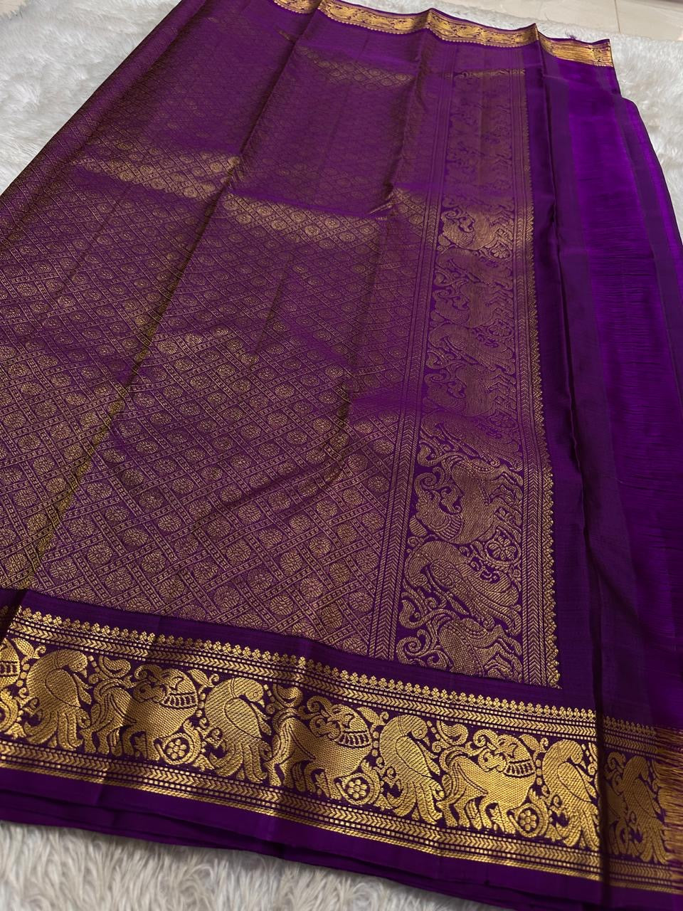Sorgavaasal Kili – Pure Silk Kanchipuram Saree in Teal with Purple Zari Kattam
Intricately handwoven with traditional zari kattam checks and adorned with exquisite zari-woven Yazhi buttas, this saree features a vibrant teal body paired with a regal purple