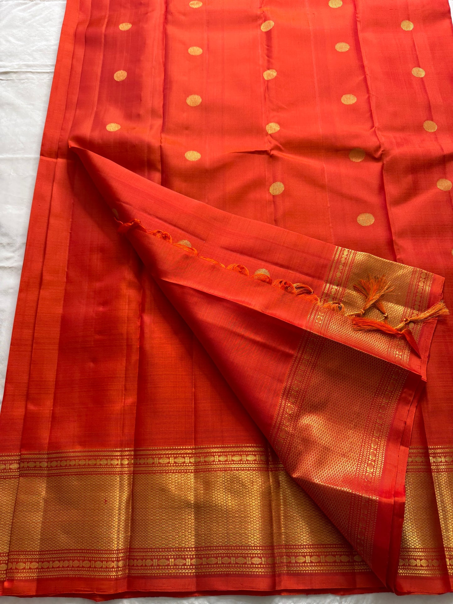 Maya
Vibrant Orange Kanchipuram Silk Saree with Lustrous Gold Coin Buttas
Handwoven Traditional Rudhraksham Seer and Intricate Arai Maadam Zari Border
Richly Crafted Pallu Featuring Elegant Gold Zari Panels for a Regal Finish