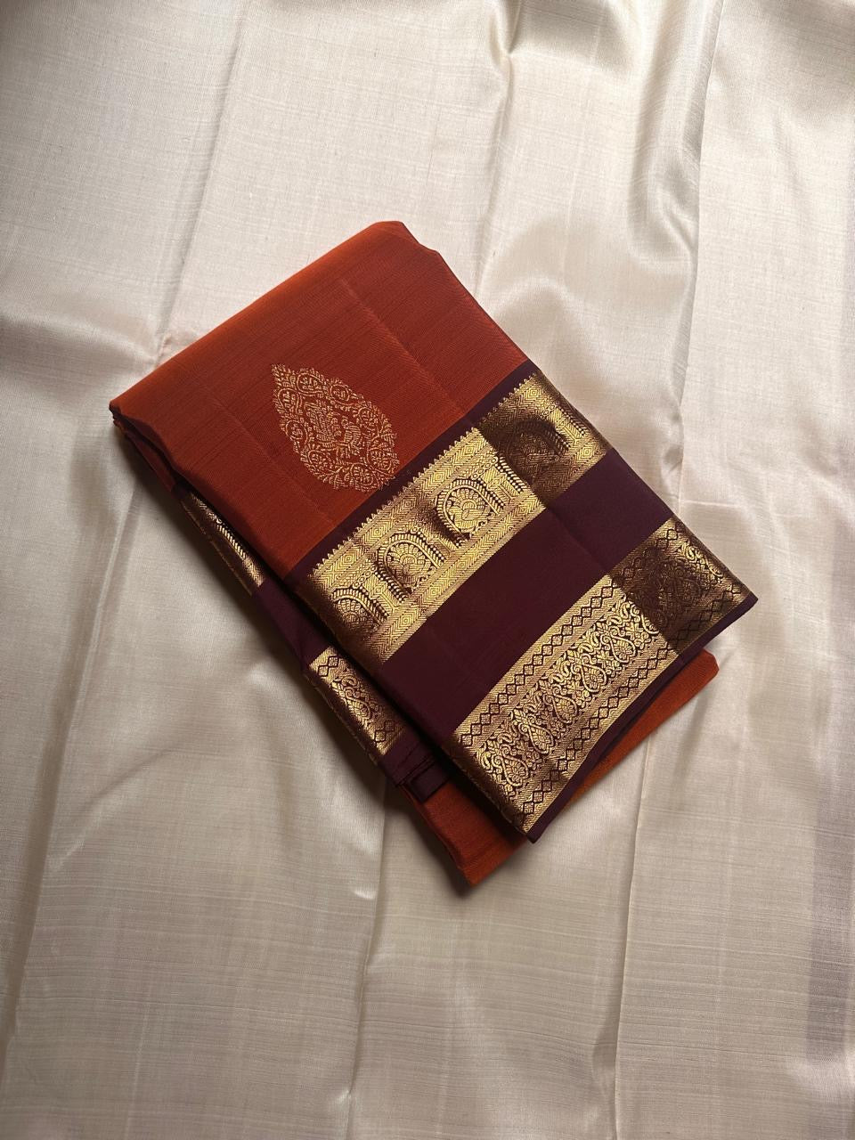 Rust Orange Choodamani — Pure Silk Kanchipuram
Rust-orange body with golden paisley buttas ✨
Deep maroon korvai borders with temple-arch zari 🌸
Grand maroon brocade pallu with elephants & florals 🪔
Silk Mark Certified • Free Shipping USA • Ships in Two