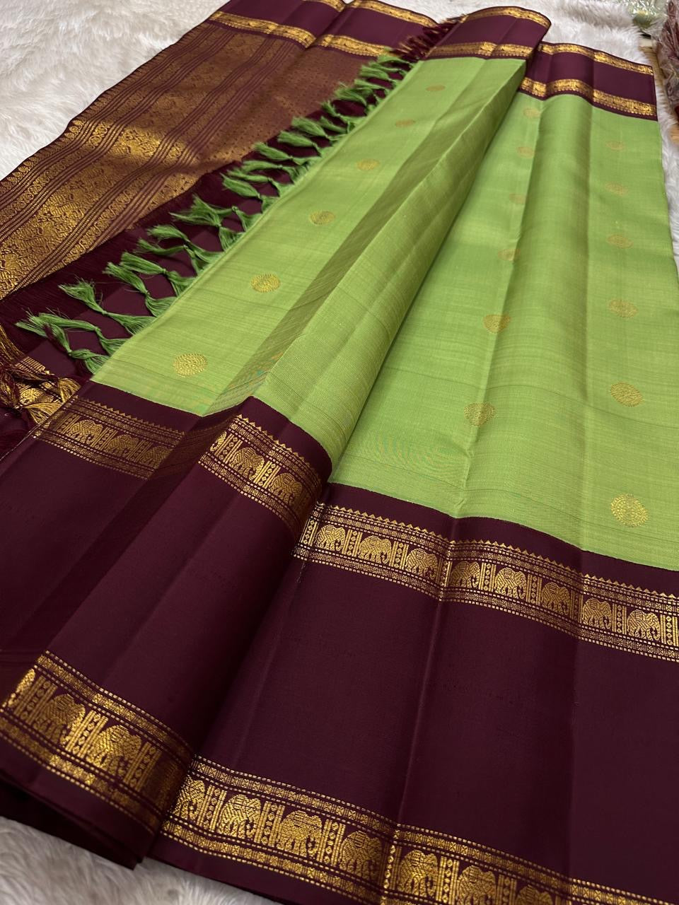 Samprada – Kanchipuram Silk Saree in vibrant cardamom Green & brown
A vibrant parrot green body meets a rich maroon border in this timeless Kanchipuram silk saree
