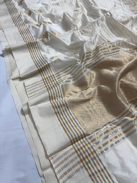 Ivory Cream Chanderi Saree with Gold Zari and Handwoven Sunflower Motifs.
A serene blend of tradition and elegance, with intricate red mina accents. Finished with alternating sona roopa stripes and a richly woven pallu for timeless festive charm