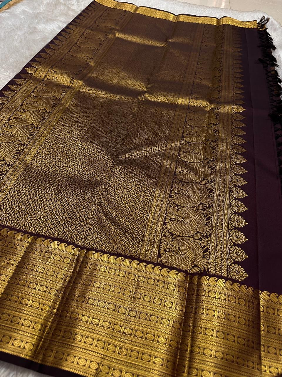 Cholai – Orchard at Dusk ✨ A pure Kanchipuram silk in deep purplish-brown, adorned with regal Gandaberunda 🦅 and delicate Kamalam 🌸 motifs. Its gold zari border layers Varisaipet, mango paisley 🥭, Rudhraksham, and Vanki for a true heritage masterpiece