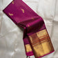 Folded magenta Kanchipuram silk saree with gold peacock buttas and rich zari border on an ivory backdrop