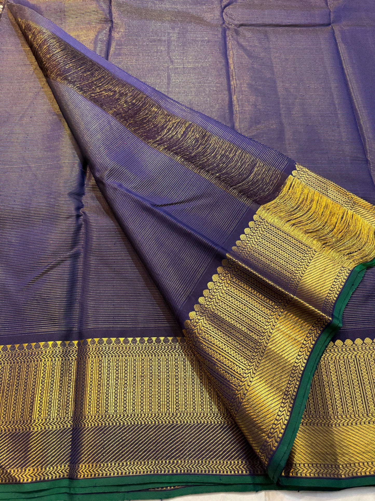 Krishna Shyama — Pure Silk Kanchipuram

Deepest purple “Shyama” body with Vairaoosi pinstripes

Temple-inspired antique gold zari borders with green selvedge

Grand striped zari pallu with hand-tied tassels

Silk Mark Certified • free shipping