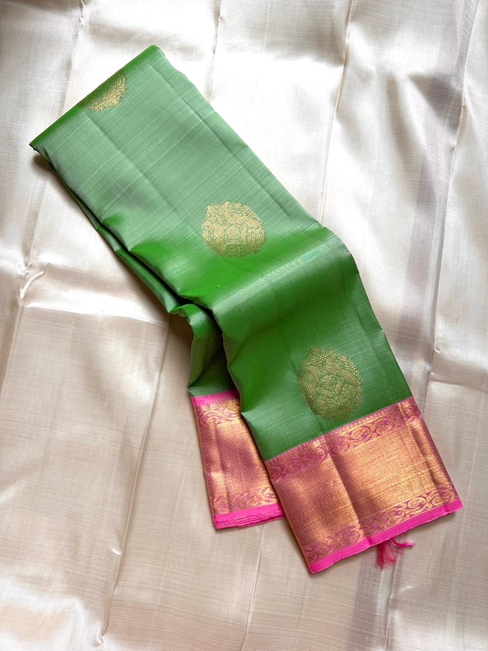 Asha ✨ – Fresh Green Pure Silk Kanchipuram Saree
with Radiant Pink Korvai Contrast Border
Gold Zari Floral Medallion Buttas on the Body
Grand Pink Brocade Pallu with Intricate Weaving