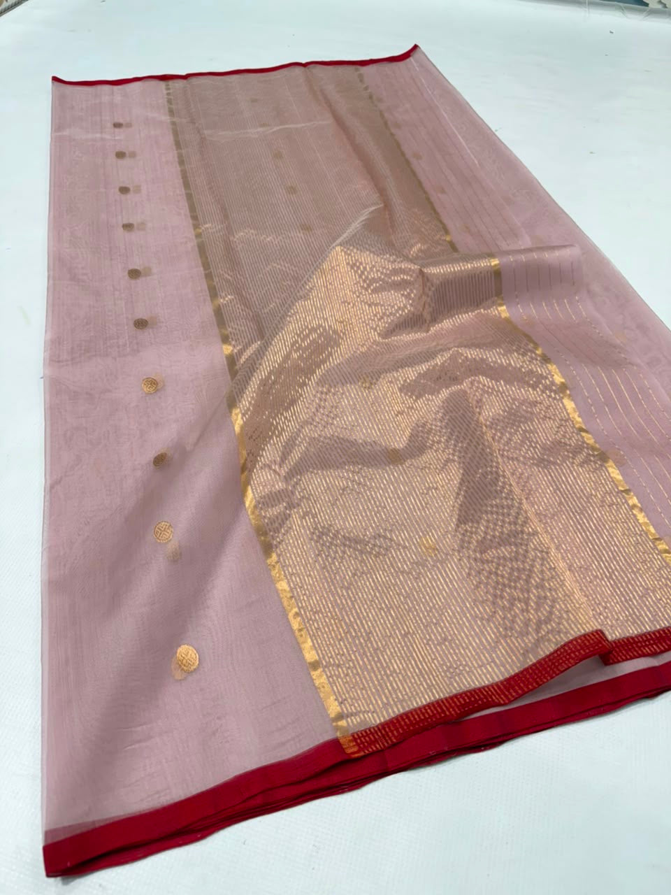 Folded Dusty Rose Chanderi saree showing the gold buttas and red contrast border