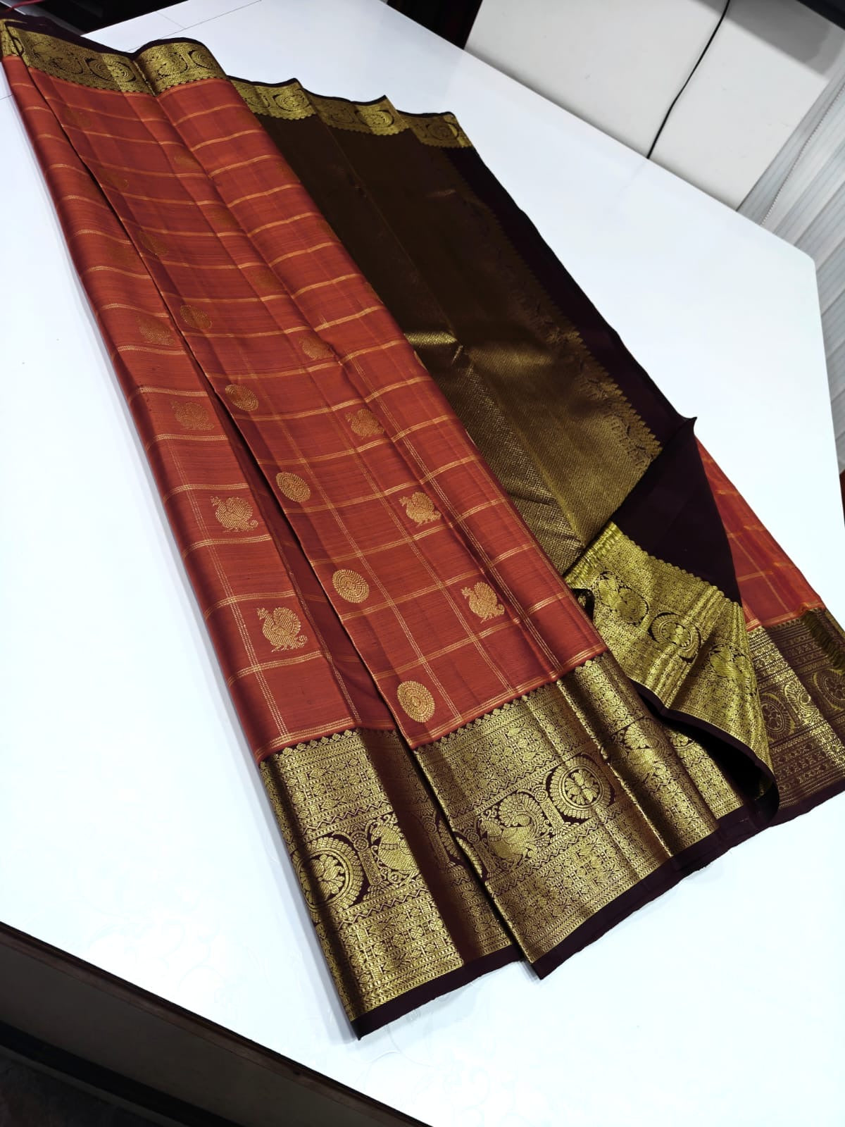 Pure Kanchipuram Silk Saree – Coral Red Checks with Gold Zari Buttas
Contrast Maroon Korvai Borders with Temple & Floral Motifs
Grand Zari Brocade Pallu
Silk Mark  | Fall & Pico Done | Blouse Stitching ($30) | ships in 2 weeks