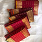 Group of folded red and maroon Kanchipuram silk sarees arranged together, each with gold zari borders and horizontal lines.