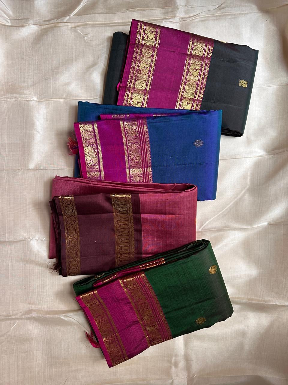 Flat-lay group of Kanchipuram silk sarees showing maroon-coffee combination and zari borders