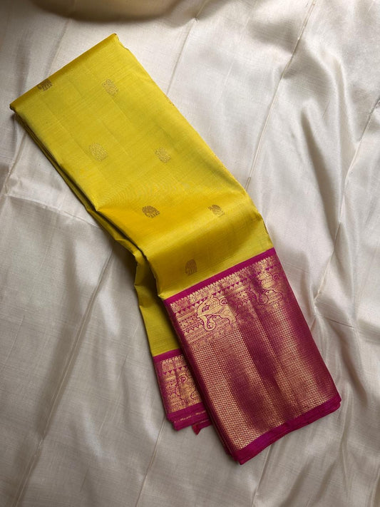 Crafted from pure Kanchipuram silk, this golden yellow saree features a broad pink border with traditional Yali motifs. The pallu is richly woven with bold elephant designs in thick zari—an elegant blend of heritage and grandeur.
