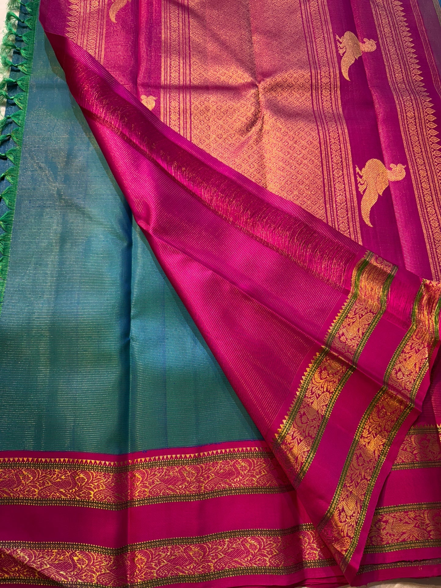 Kavi ✨ – Pure Kanchipuram Silk Saree
Teal Blue Silk Body with Lustrous Shot Weave
Rich Magenta Contrast Border in Gold Zari
Grand Pallu with Intricate Kili (Parrot) Motifs
Magenta Blouse with Matching Zari Border Silk Mark Certified, delivery in 2 weeks