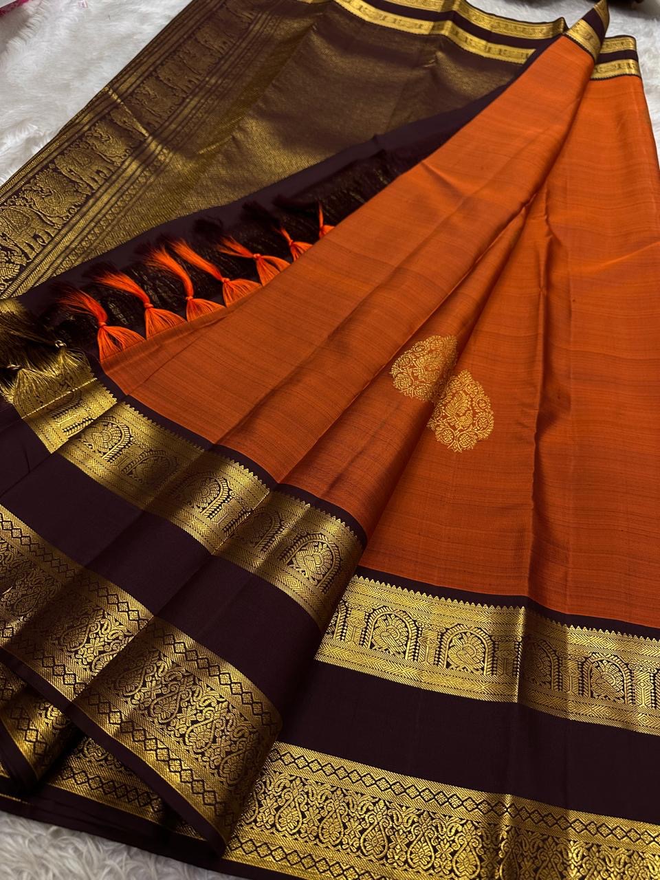 Rust Orange Choodamani — Pure Silk Kanchipuram
Rust-orange body with golden paisley buttas ✨
Deep maroon korvai borders with temple-arch zari 🌸
Grand maroon brocade pallu with elephants & florals 🪔
Silk Mark Certified • Free Shipping USA • Ships in Two