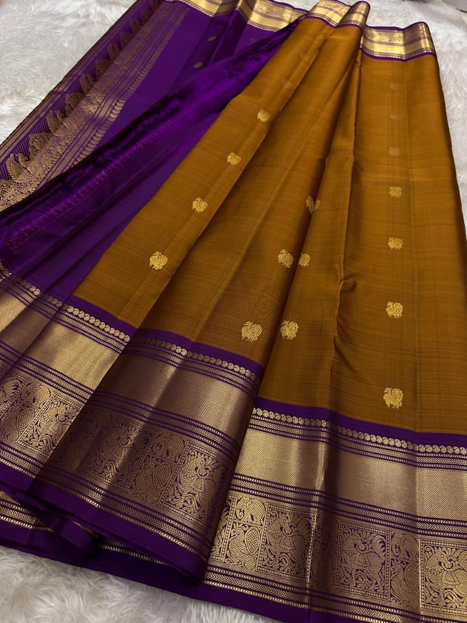 Ponvandu & Purple Butta — Pure Kanchipuram Silk Saree
Antique mustard body with gold zari buttas & rich purple borders
Peacock-woven zari motifs and temple serrations across the grand pallu
Silk Mark Certified • Free Shipping within USA • Ships in Two Wee