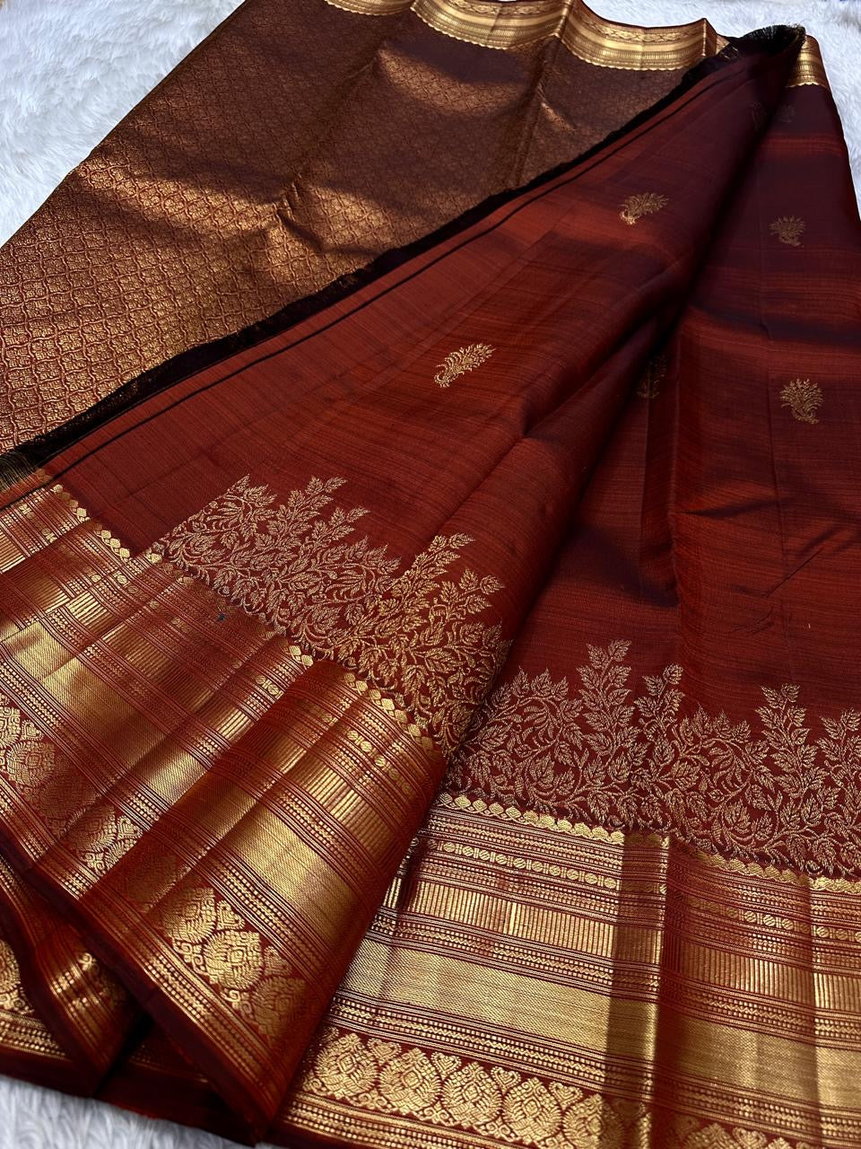 Gilded Rust – Pure Kanchipuram Silk Saree
Deep rust body with delicate paisley zari buttas 🌿
Antique-gold border featuring kaddi stripes & floral motifs ✨
Grand brocade pallu with lattice jaal & floral vines 🕊️

Silk Mark Certified, delivery in 2 weeks