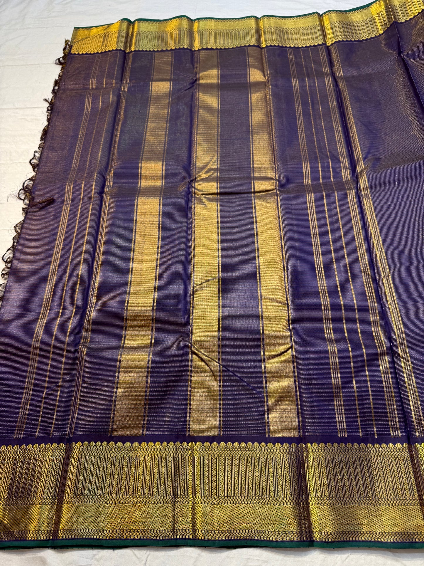 Krishna Shyama — Pure Silk Kanchipuram

Deepest purple “Shyama” body with Vairaoosi pinstripes

Temple-inspired antique gold zari borders with green selvedge

Grand striped zari pallu with hand-tied tassels

Silk Mark Certified • free shipping