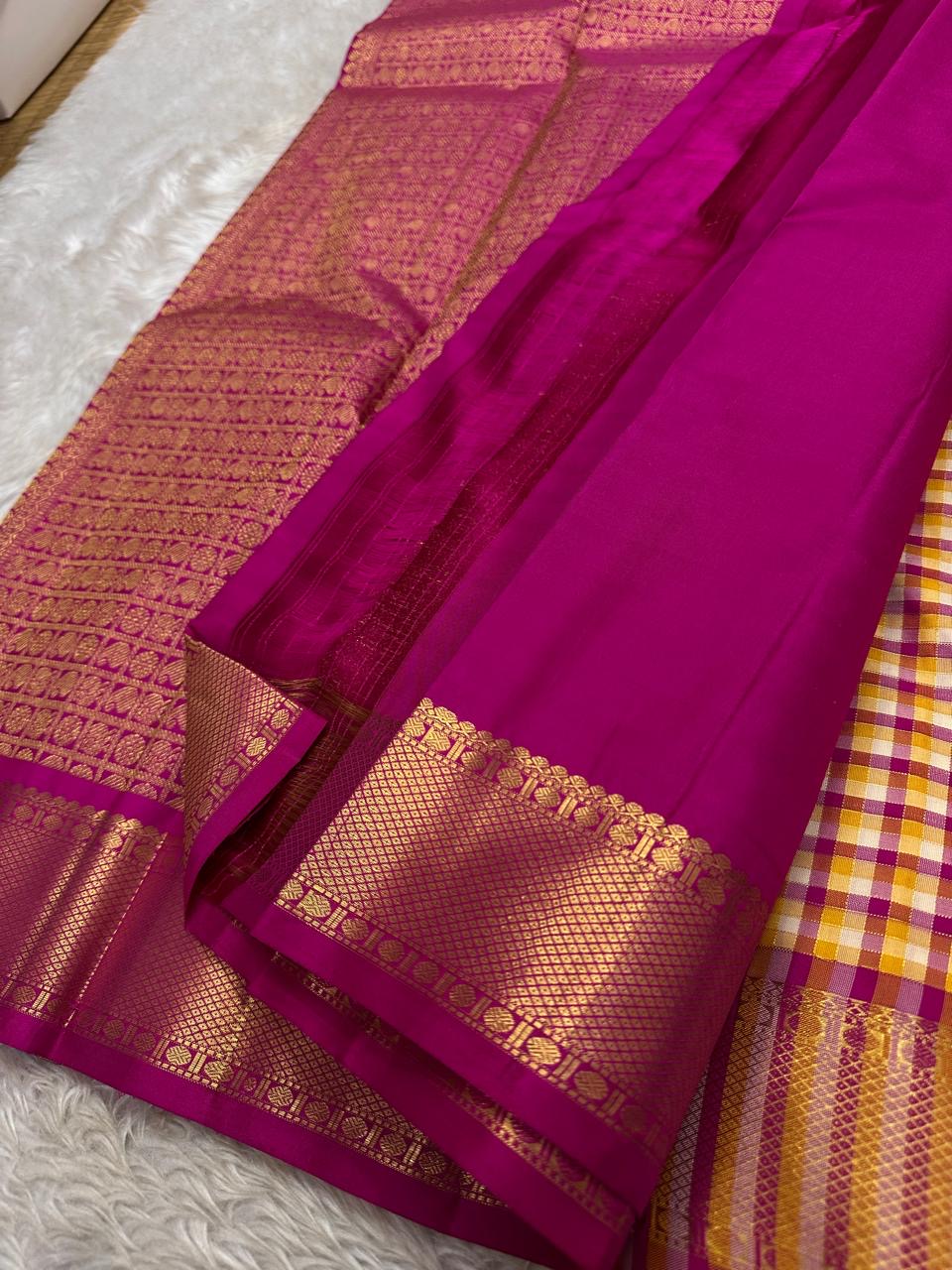 A classic Kanchipuram in Pattani Kattam checks with pink, magenta, mustard, and cream.
Finished with a contrast pink border and pallu.
Paisley and chakram motifs in a graceful grid add timeless charm.