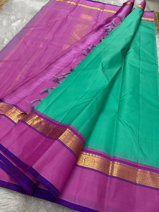 Jade Blossom – Pure Silk Kanchipuram Saree
Elegant Jade-Teal Body with Lustrous Weave 🌿
Rani-Magenta Contrast Border with Gold Zari ✨ purple selvedge 
Grand Magenta Pallu in Lattice Design
Silk Mark Certified | ships in 2 weeks