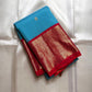 Folded sky blue Kanchipuram silk saree with red zari woven border and gold pallu
