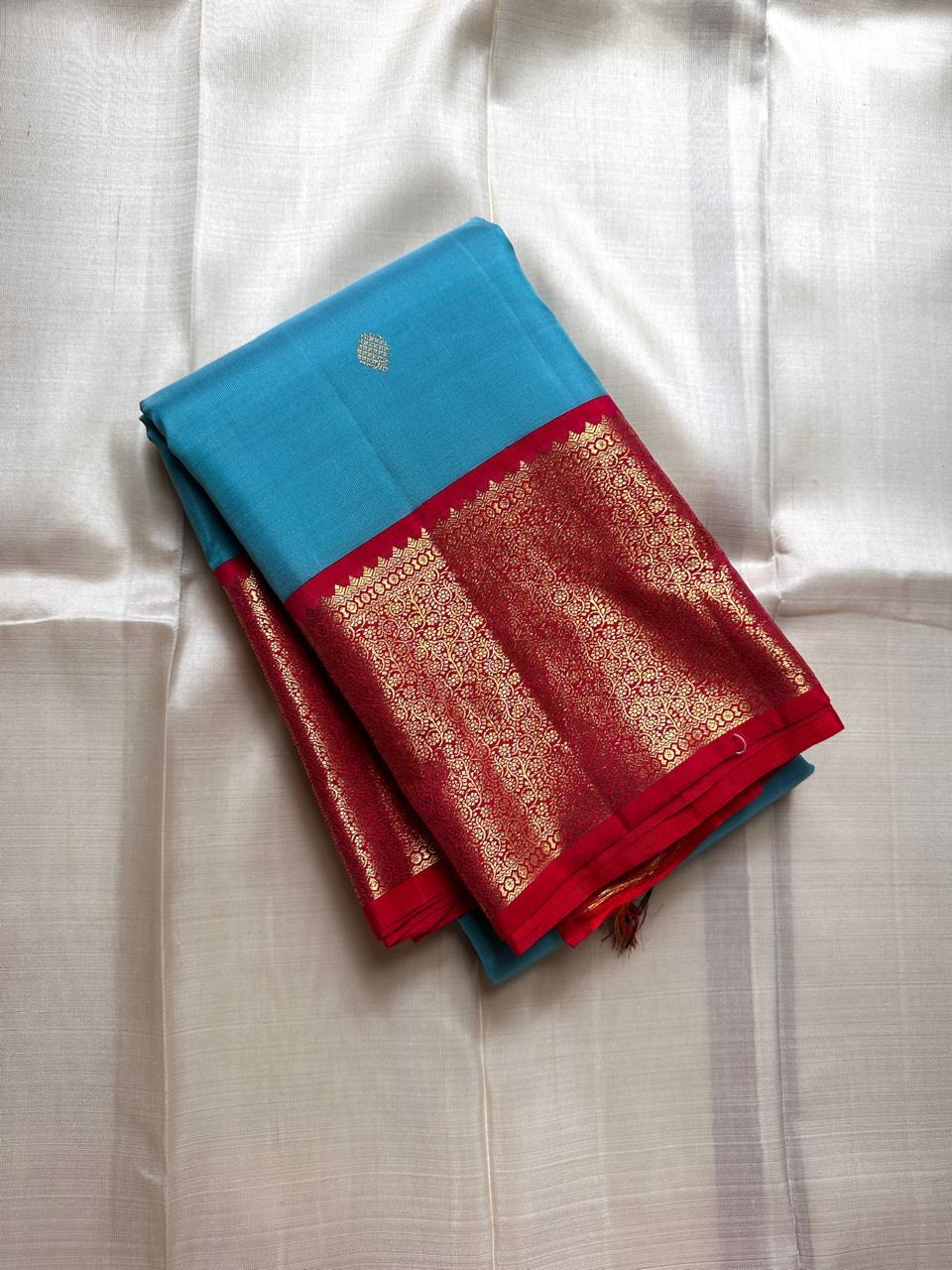 Folded sky blue Kanchipuram silk saree with red zari woven border and gold pallu