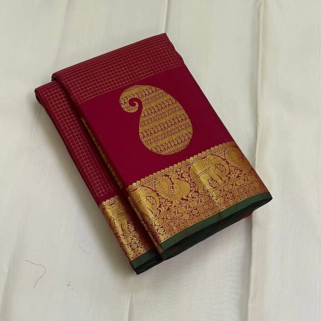 Ushas, Deep Arakku Red Pure Kanchipuram Silk Saree
Radiant Oosi Kattam body with ornate Paisley 2gm Zari
Vanasringaram,Muthuseer,Kamalam border with Fishpettu detailing
Exquisite diamond-pet grid Zari pallu, richly finished with a bold deep green selvedge
