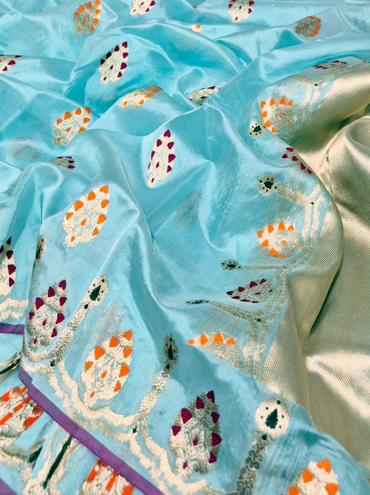 Close view of Aqua Blue handloom Chanderi silk with gold-toned motifs accented in magenta orange and green