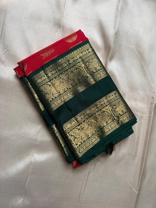 Sindoor red Kanchipuram silk saree folded with elephant zari woven green border