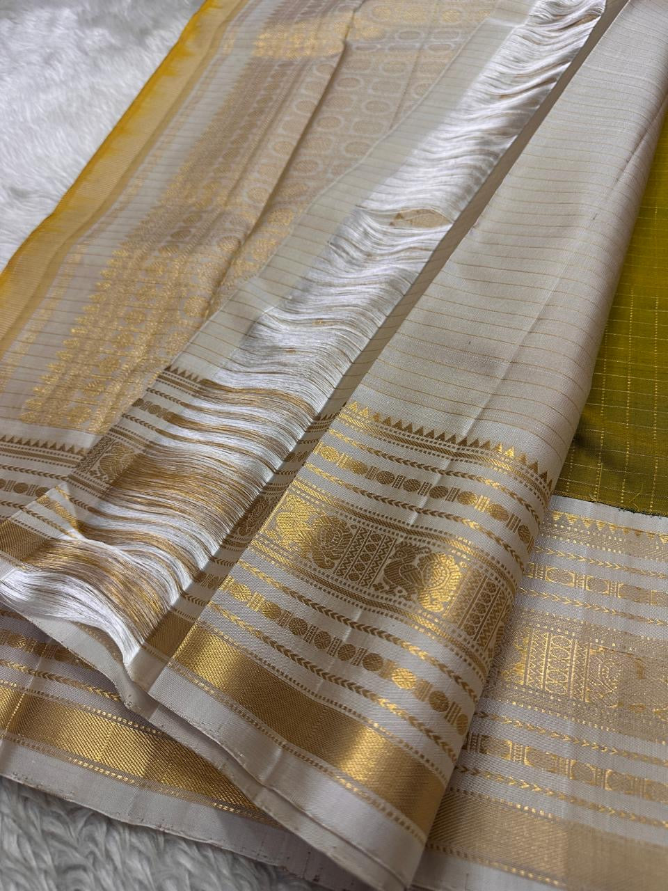 Luminous Lemon-Olive Green — White Korvai Kanchipuram

Pure Silk | Vairaoosi Checks | Korvai Contrast Borders

Classic White & Gold Pallu with Coin Jaal Motifs

Perfect for Muhurtham, Haldi & Temple Occasions

Silk Mark Certified | Free Shipping | Shi