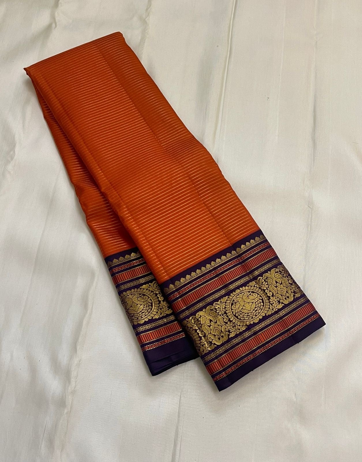 Kesari Annapakshi Chakram
Pure Kanchipuram Silk Saree – Vibrant Kesari Orange Body with Gold Zari Chakram Buttas
Deep Purple Korvai Borders with Majestic Annapakshi & Floral Motifs
Grand Purple Zari Pallu. Silk mark certified , ships in 2 weeks