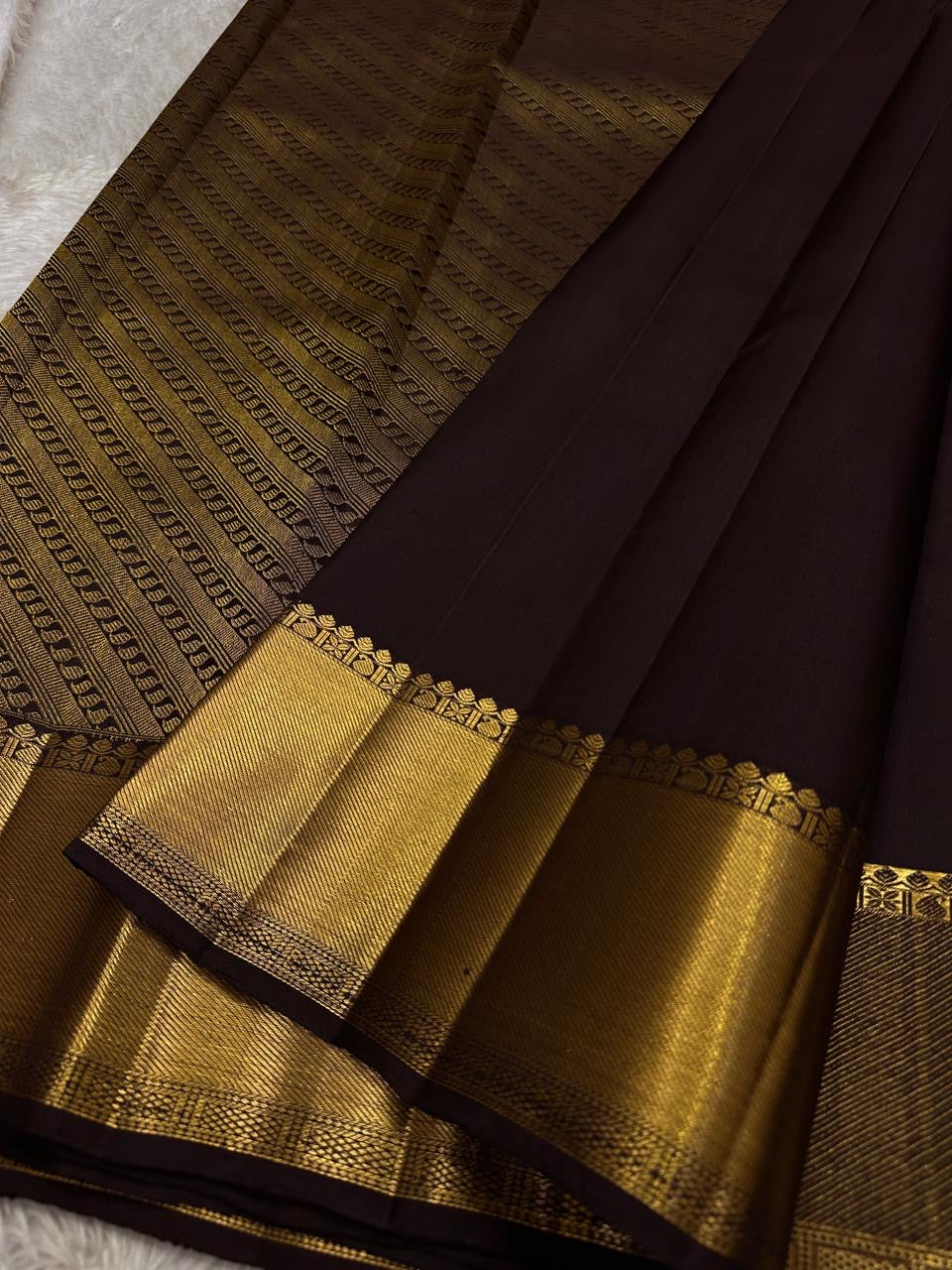Agnika – Dark Espresso Kanchipuram Silk Saree with Mayil Chakram Butta
Fiery and regal, Agnika features a rich dark espresso silk body with intricate Mayil Chakram (peacock) motifs and a shimmering zari border—an elegant ode to South Indian tradition.
