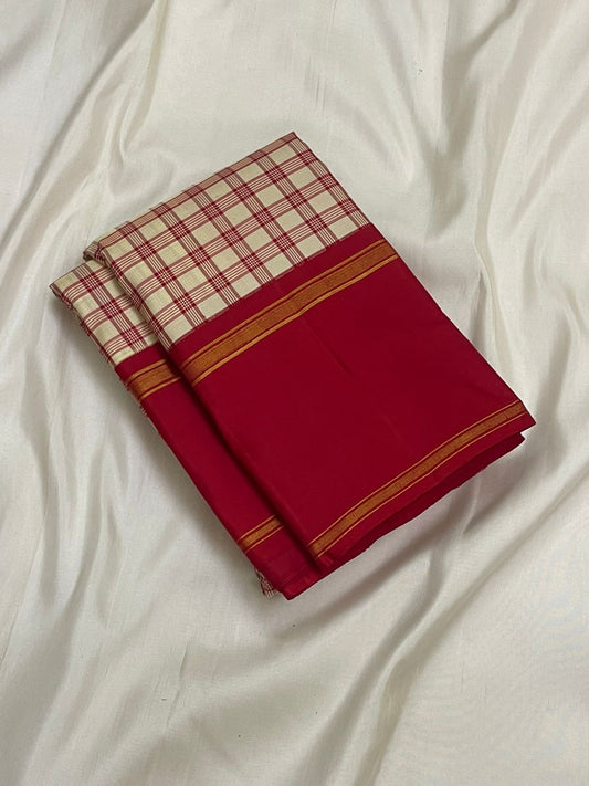 Folded cream and red checked silk saree with a deep red border and thin gold zari woven lines on white fabric.