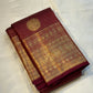 Pavila – Rich brown pure silk Kanchipuram saree in shimmering zari kattam checks. Layered varisaipet borders feature peacocks, yazhi, and rudraksham motifs in ornate zari. A bold broad yazhi adai motif lends ceremonial elegance. Grand  ornate Pallu