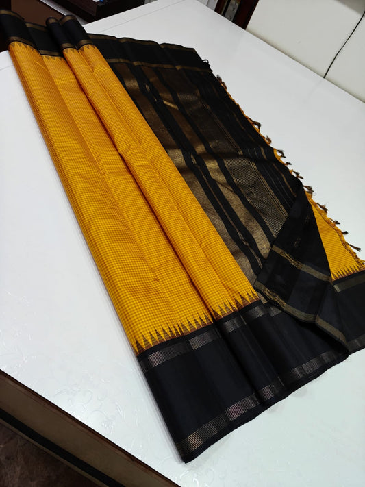 Ochre Dawn – Pure Silk Kanchipuram Saree
Mustard Body with Mini Checks (Pattani Kattam) 🌅
Black Korvai Border with Temple Gopuram Edging ✨
Grand Black Pallu with Elegant Zari Stripes
Silk Mark Certified | ships in two weeks