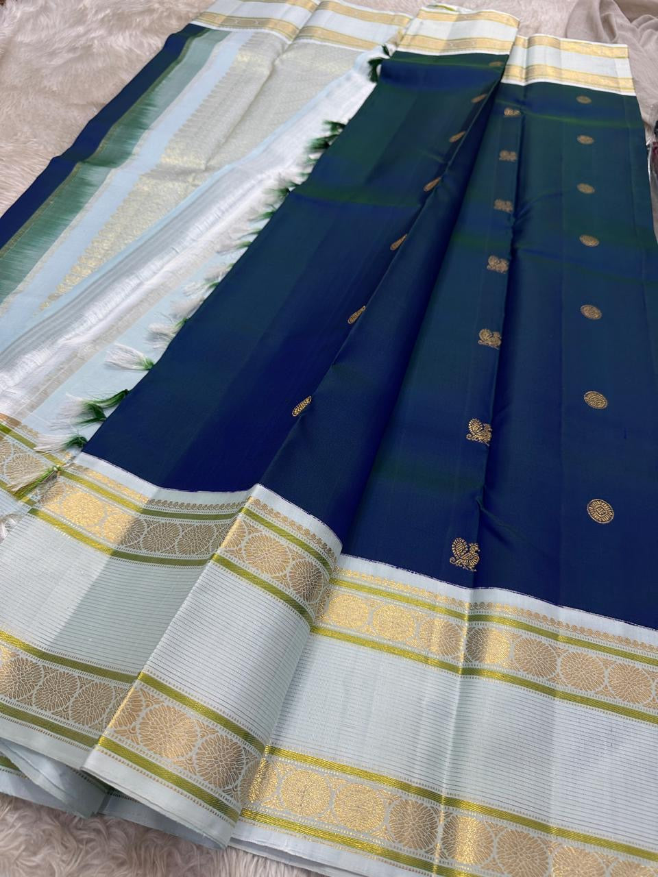 Mayil Kazhuthu ✨ – Peacock’s Neck Kanchipuram Pure Silk Saree
Korvai Royal-Purple Border with Peacock & Floral Zari Vines
Body Embellished with Gold Kamalam (Lotus) Buttas
Grand Gold Zari Pallu with Traditional Motifs & Hand-knotted Tassels
Silk Mark
