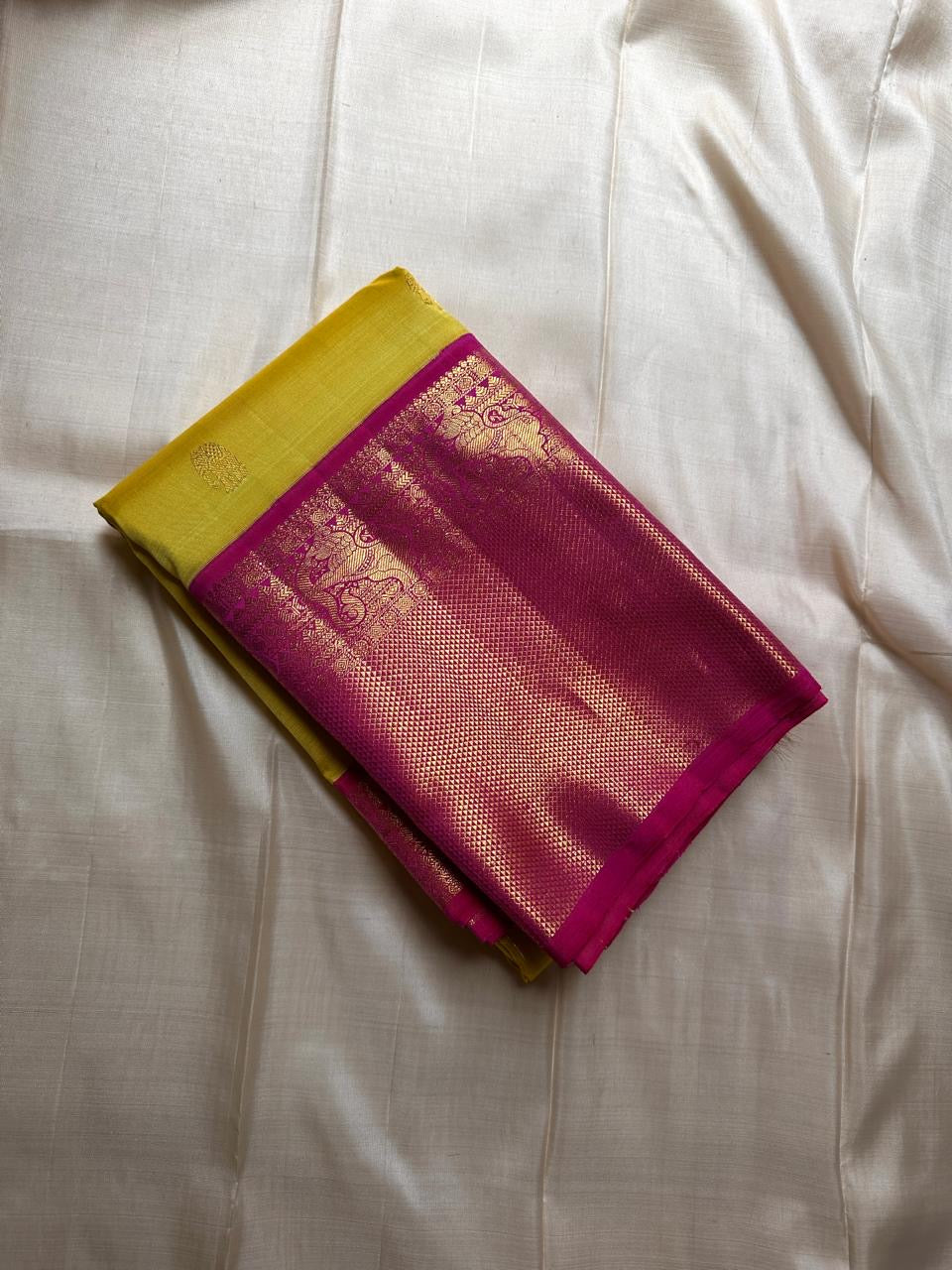 Crafted from pure Kanchipuram silk, this golden yellow saree features a broad pink border with traditional Yali motifs. The pallu is richly woven with bold elephant designs in thick zari—an elegant blend of heritage and grandeur.