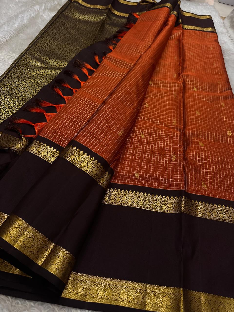 Gilded Rust Kattam – Pure Silk Kanchipuram Saree

Rust-orange kattam (checks) body with petite zari buttas ✨
Deep brown  korvai border with intricate gold zari design 🌸
Grand zari-rich pallu 💛
Silk Mark Certified ✅ | ships in two weeks