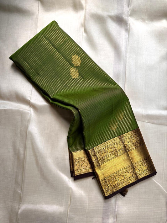 Forest Gold – Pure Kanchipuram Silk Saree
Leaf-green body with fine pin stripes.
Zari leaf buttas for subtle sparkle.
Coffee-maroon korvai border in antique gold.

Silk Mark Certified, delivery in 2 weeks