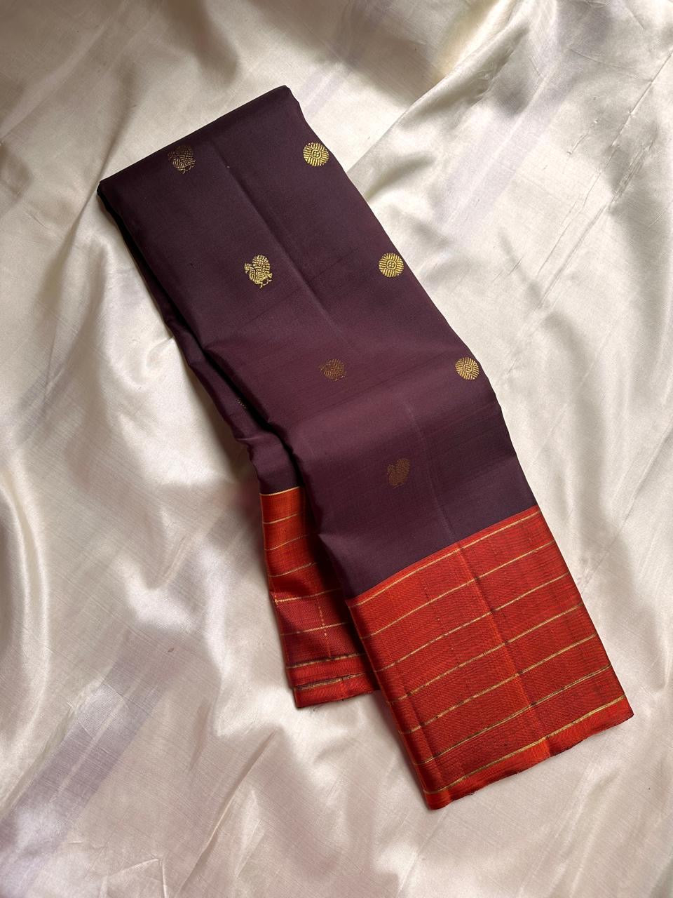 Minmini – Deep brown Pure Kanchipuram Silk Saree with Gold Zari Buttas, Vibrant Orange Checked Border in Zari Kattam Weave & Ornate Gold Brocade Pallu with Traditional Motifs