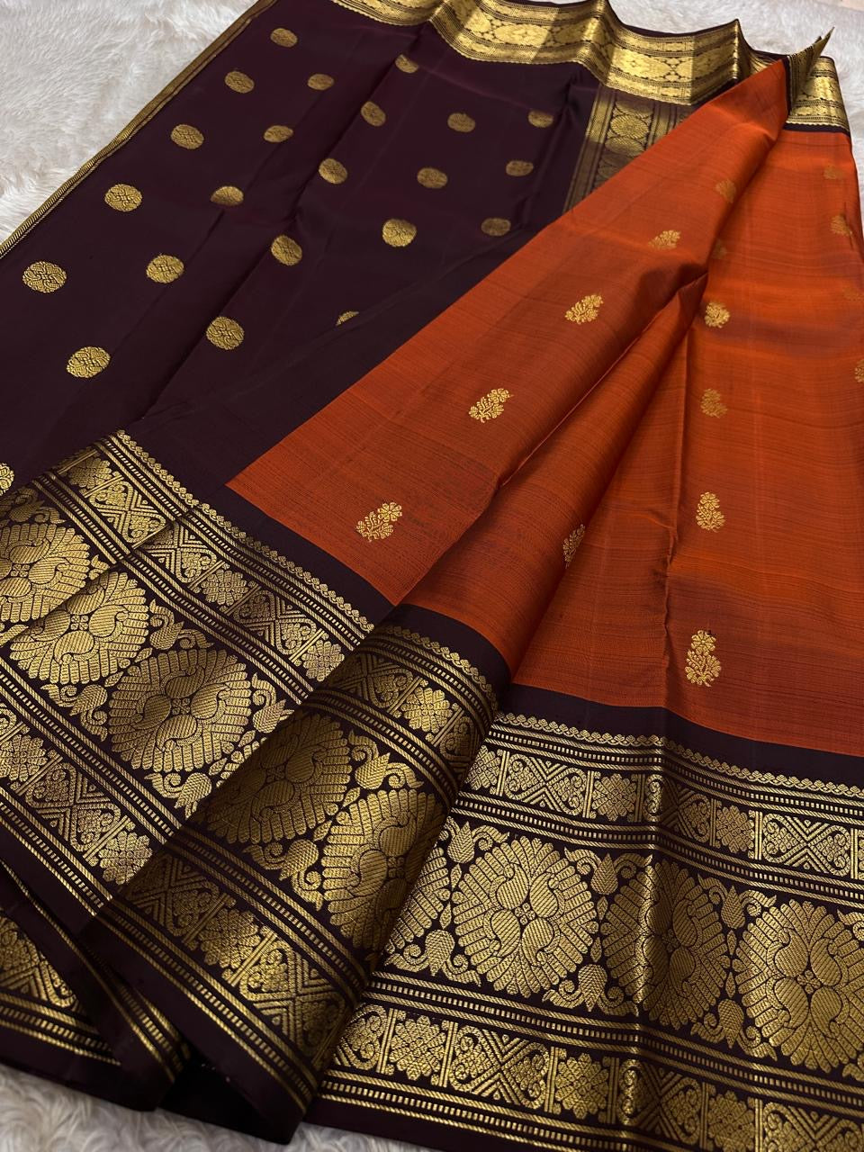 Rust Orange Coffee Brown — Flower Butta | Pure Kanchipuram Silk Saree
Rust-orange body with dainty zari-woven flower buttas and grand coffee-brown korvai borders rich in antique-gold floral medallions.
Silk Mark Certified • Blouse Stitching Available ($30