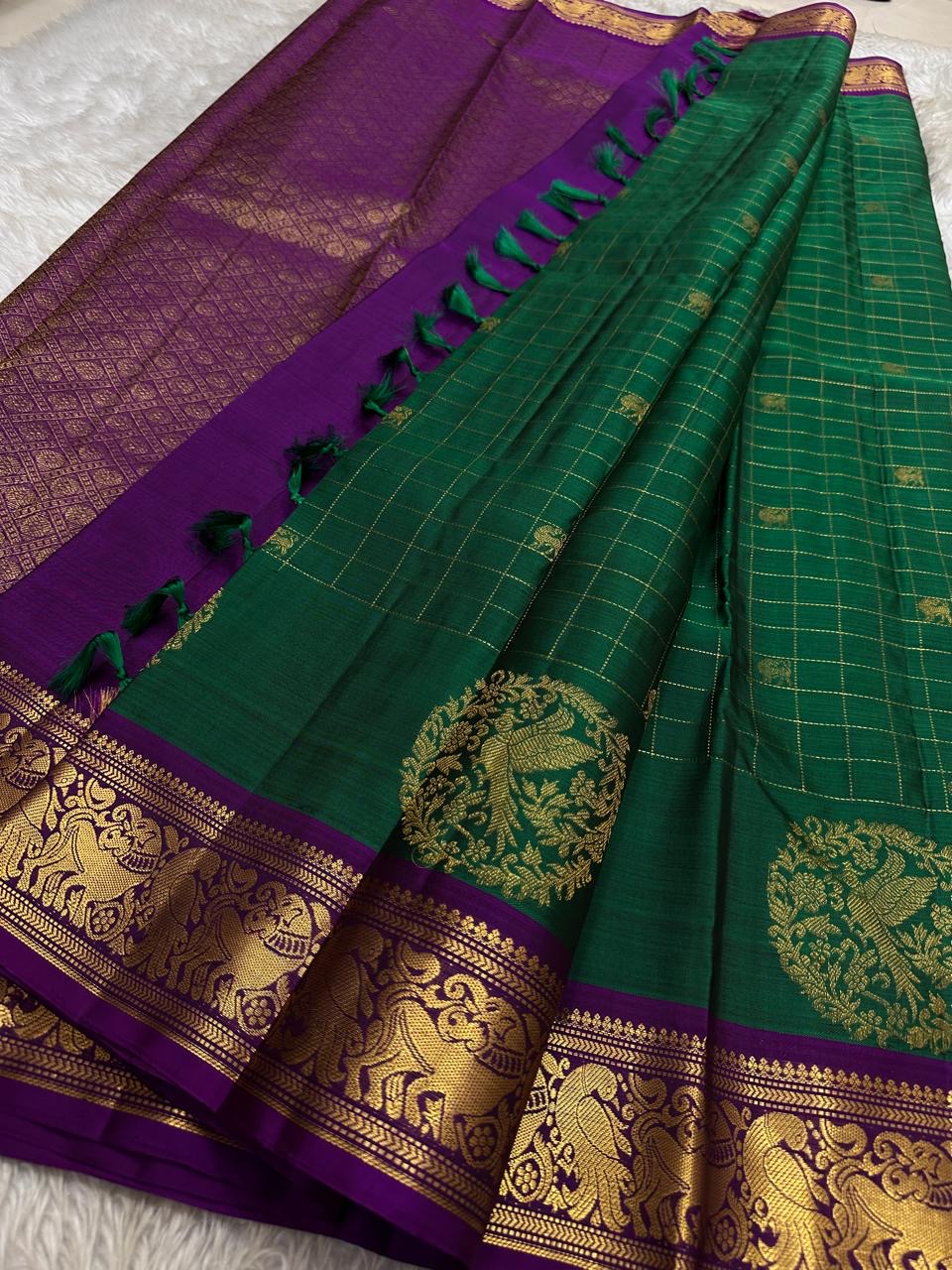 Sorgavaasal Kili – Pure Silk Kanchipuram Saree in Teal with Purple Zari Kattam
Intricately handwoven with traditional zari kattam checks and adorned with exquisite zari-woven Yazhi buttas, this saree features a vibrant teal body paired with a regal purple