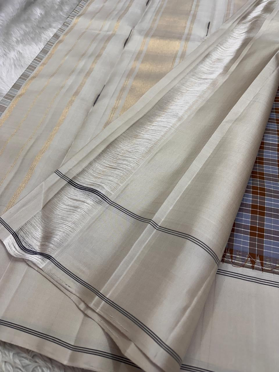 Nirai – Pure Kanchipuram Silk in Sandal, Grey & Mauve Checks.
Framed with a subtle sandal border and navy thread stripes, the saree features a striking pallu woven with thazhampoo reku and beautiful mullai mottu motifs in navy silk thread