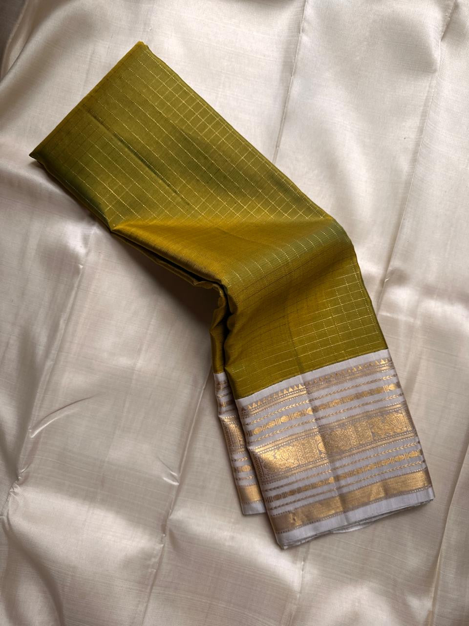 Luminous Lemon-Olive Green — White Korvai Kanchipuram

Pure Silk | Vairaoosi Checks | Korvai Contrast Borders

Classic White & Gold Pallu with Coin Jaal Motifs

Perfect for Muhurtham, Haldi & Temple Occasions

Silk Mark Certified | Free Shipping | Shi