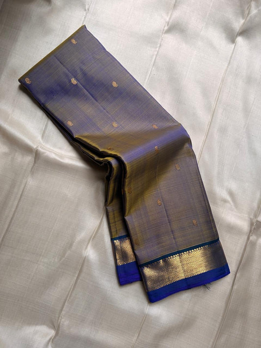 Varnam – Dove Tail Gray & Peacock Blue Kanchipuram Silk Saree. Featuring rich gold paisley buttas, a bold chevron zari border, and pure handloom silk craftsmanship ✨ Silk Mark Certified | Blouse Stitching Available | Free USA Shipping