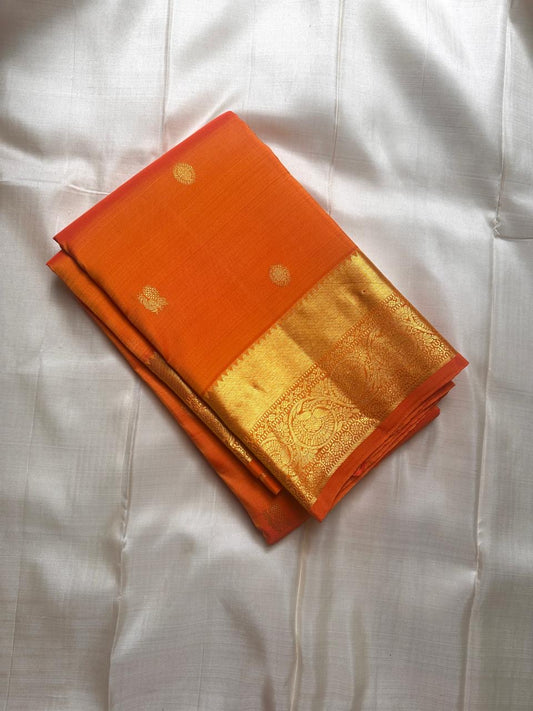 Agnika – orange Kanchipuram Silk Saree with Mayil Chakram Butta & Orange Border Fiery and regal, Agnika is a pure Kanchipuram silk saree featuring a rich red body adorned with intricate Mayil Chakram buttas.