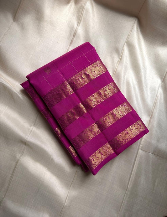 vasantham  Fuchsia pink – Handwoven Kanchipuram Silk Saree A poem in Fuchsia silk. The body glows in a serene vibrant Fuchsia, softly accented by delicate gold vertical lines and dainty gold zari buttas that glint like little blessings.