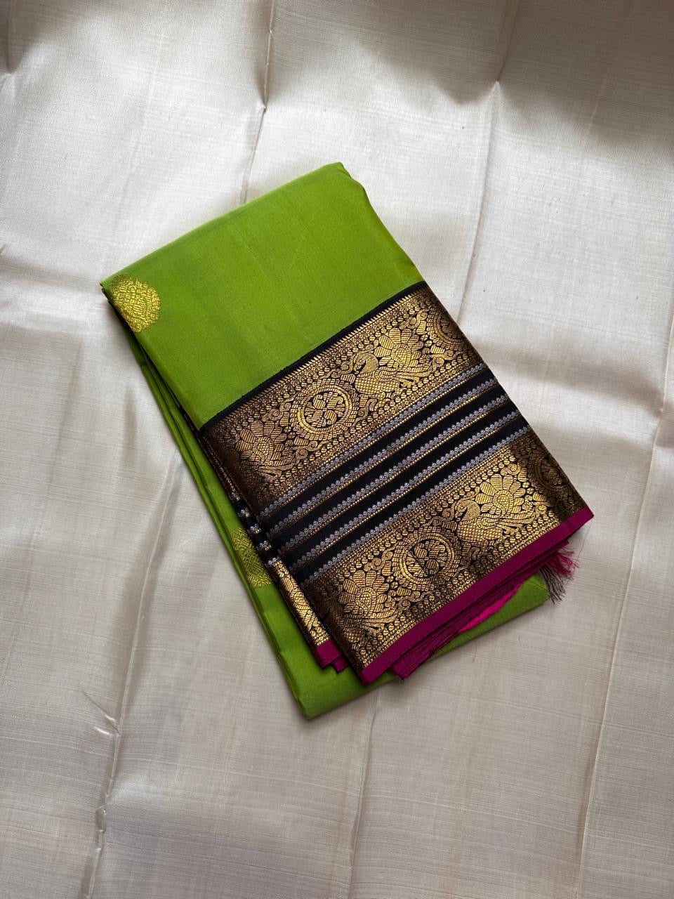 Kili Pachai — Pure Silk Kanchipuram Saree
Parrot-Green Body with Gold Buttas ✨
Black Korvai Borders with Peacock Medallions 🦚
Black Brocade Pallu • Contrast Black Blouse with Zari 🌸
Silk Mark Certified • Free Shipping within USA • Ships in Two Weeks