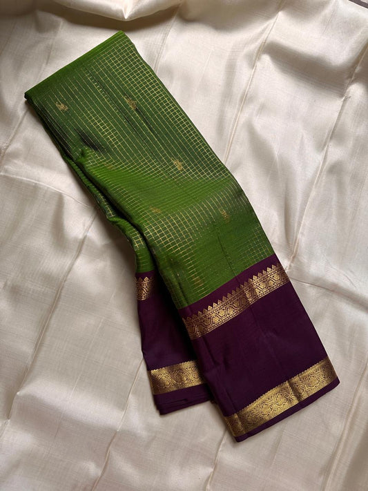 Iravati – Earthy Green Kanchipuram Pure Silk Saree
A graceful weave in a rare earthy green tone, adorned with gold zari kattam and butta.
Accented by a rich plum rettapet border with delicate flower vine motifs.