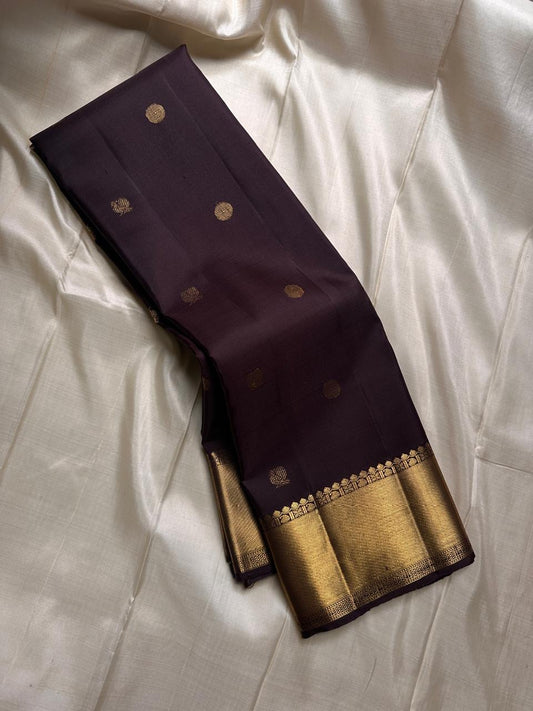 Agnika – Dark Espresso Kanchipuram Silk Saree with Mayil Chakram Butta
Fiery and regal, Agnika features a rich dark espresso silk body with intricate Mayil Chakram (peacock) motifs and a shimmering zari border—an elegant ode to South Indian tradition.
