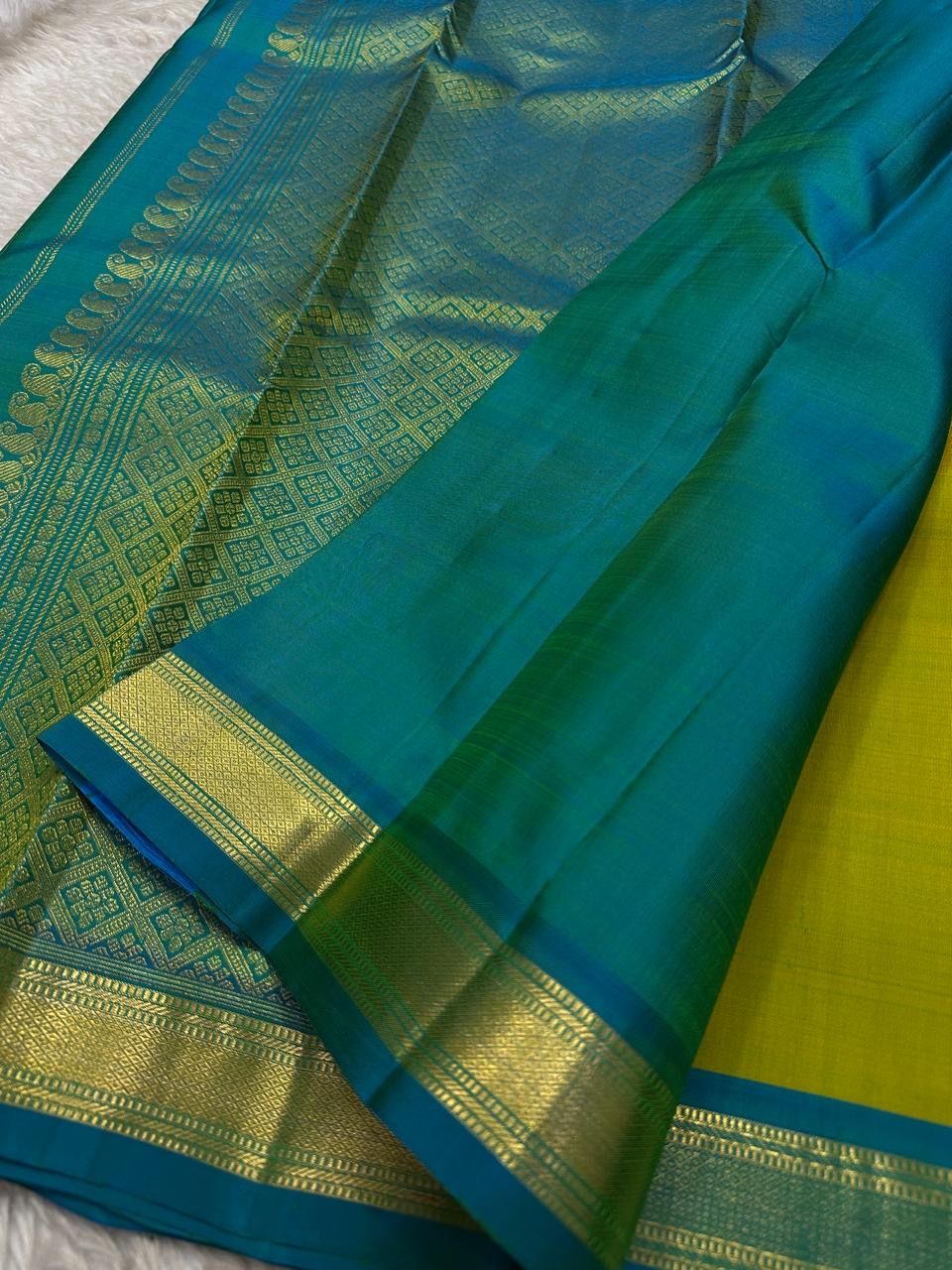 Citrus and Teal – Pure Kanchipuram Silk Saree
Dual-tone body in parrot green and turmeric.
Elegant gold leaf buttas across the drape.
Teal korvai border
Rich teal pallu with diamond jaal and temple motifs.

Silk Mark Certified, delivery in 2 weeks