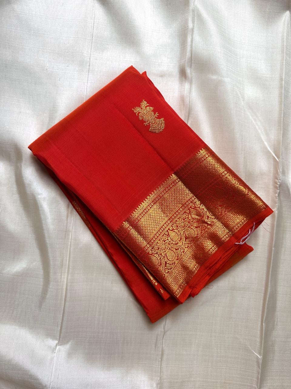 Red Kanchipuram silk saree with gold peacock buttas and rich gold zari border, pure handloom silk.

