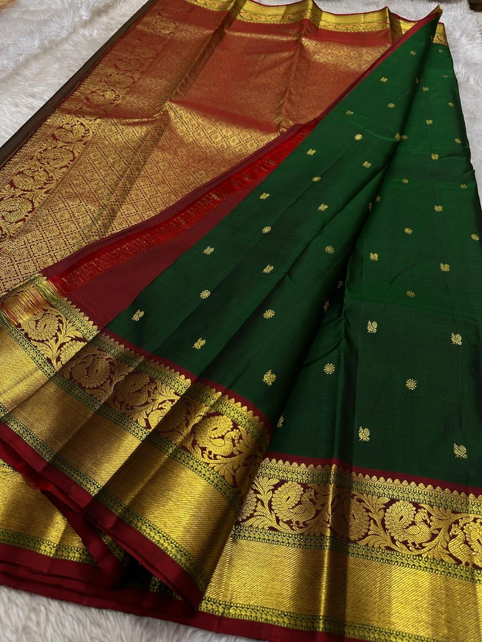 Emerald Glow ✨ – Pure Kanchipuram Silk Saree

Deep Green Body with Gold Floral Buttas

Maroon Korvai Border with Peacock & Floral Zari Motifs

Grand Gold Zari Brocade Pallu with Diamond Lattice Weave

Silk Mark Certified | Fall & Pico Done | Blouse Stitch